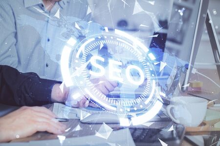 Multi exposure of seo icon with man working on computer on background. Concept of search engine optimization.の写真素材