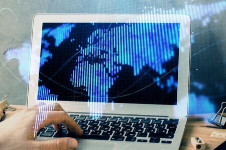 Double exposure of businessman working on laptop on background. International business hologram in...
