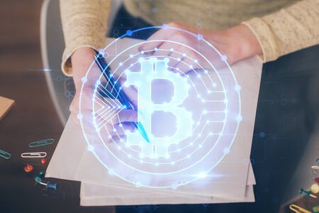 Cryptocurrency hologram over woman's hands writing background. Concept of blockchain. Multi exposureの写真素材
