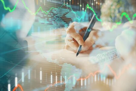 Financial forex graph displayed on hands taking notes background. Concept of research. Multi...