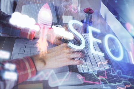 Double exposure of seo icon with man working on computer on background. Concept of search engine optimization.の写真素材