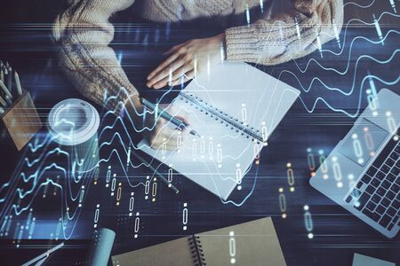 Forex graph on hand taking notes background. Concept of research. Double exposure