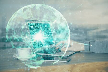 Double exposure of businessman working on laptop on background. International business hologram in front. Concept of success.の写真素材