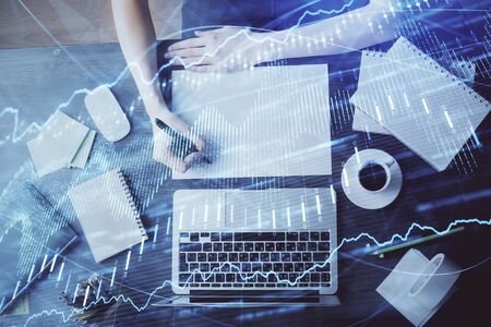 Financial graph displayed on womans hand taking notes background. Concept of research. Multi exposureの写真素材