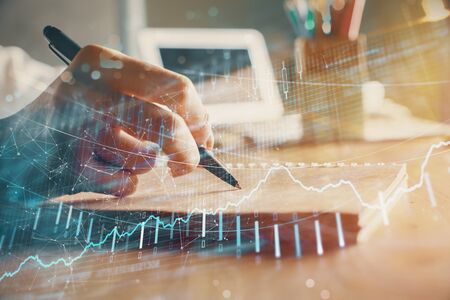 Financial forex charts displayed on womans hand taking notes background. Concept of research. Double exposureの写真素材