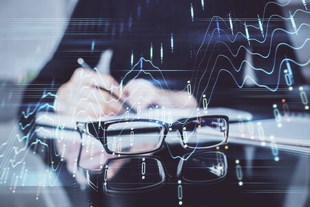 Forex chart hologram on hand taking notes background. Concept of analysis. Double exposureの写真素材