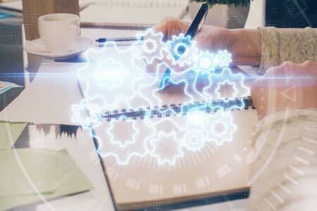 International business hologram over womans hands taking notes background. Concept of success. Double exposureの写真素材