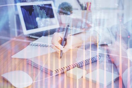 Financial charts displayed on womans hand taking notes background. Concept of research. Double exposureの写真素材