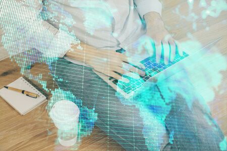 Double exposure of businessman working on laptop on background. International business hologram in front. Concept of success.の写真素材