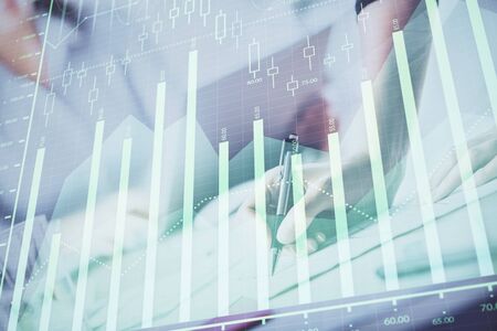 A woman hands writing information about stock market in notepad. Forex chart holograms in front. Concept of research. Double exposureの写真素材