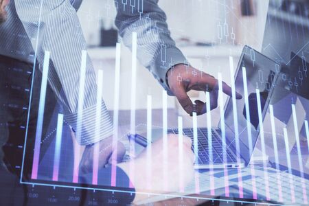 Double exposure of graph with man typing on computer in office on background. Concept of hard work....