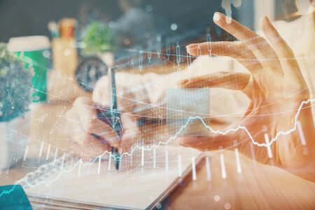 Forex chart displayed on womans hand taking notes background. Concept of research. Multi exposureの写真素材