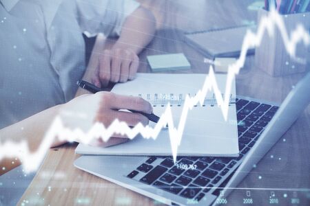 Financial charts displayed on womans hand taking notes background. Concept of research. Double exposureの写真素材