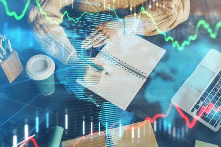 Forex graph on hand taking notes background. Concept of research. Double exposure