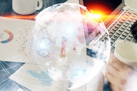 Double exposure of businessman working on laptop on background. International business hologram in...