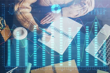 Forex graph on hand taking notes background. Concept of research. Double exposure