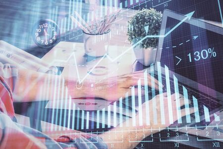 Double exposure of stock graph with businessman typing on computer in office on background. Concept of hard work.の写真素材