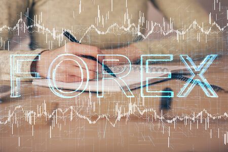 Hands writing information about stock market in notepad. Forex chart holograms in front. Concept of research. Multi exposureの写真素材