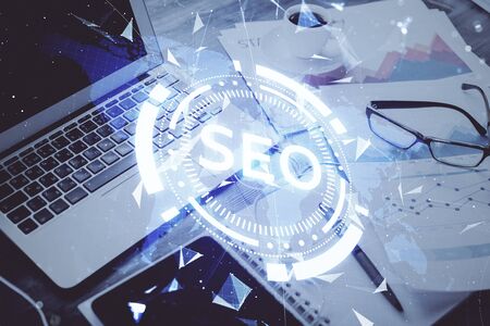 Double exposure of table with computer and seo drawing hologram. Search optimization concept.の写真素材