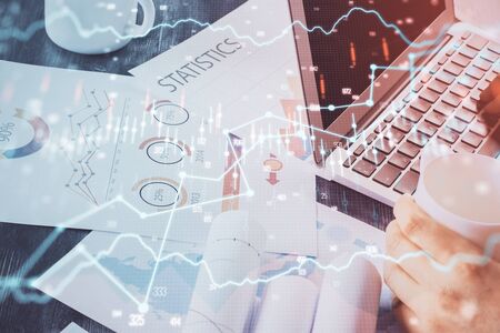 Double exposure of stock graph with businessman typing on computer in office on background. Concept of hard work.の写真素材