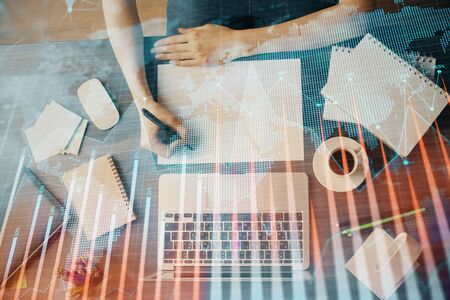 Financial graph displayed on womans hand taking notes background. Concept of research. Multi exposureの写真素材