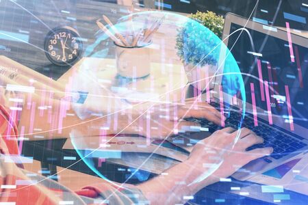 Double exposure of stock graph with businessman typing on computer in office on background. Concept of hard work.の写真素材