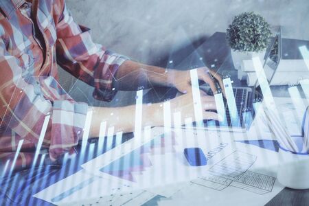 Double exposure of stock graph with businessman typing on computer in office on background. Concept of hard work.の写真素材