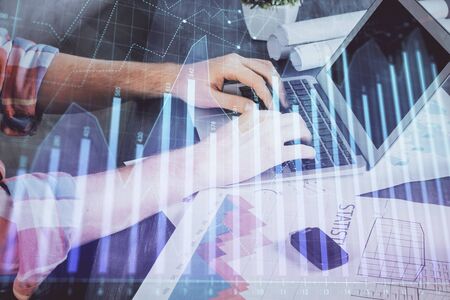 Double exposure of stock graph with businessman typing on computer in office on background. Concept of hard work.の写真素材