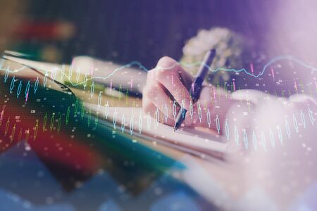 Financial forex graph displayed on hands taking notes background. Concept of research. Multi exposureの写真素材