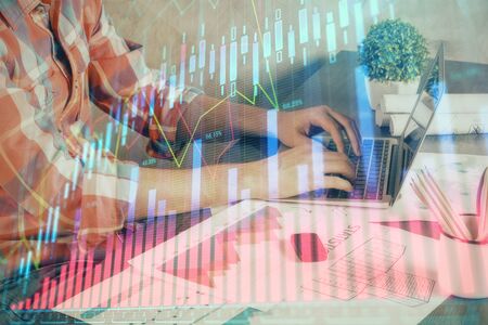 Double exposure of stock graph with businessman typing on computer in office on background. Concept of hard work.の写真素材