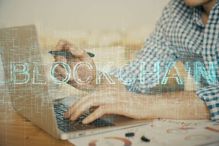 Blockchain theme hologram with man working on computer on background. Concept of crypto chain....
