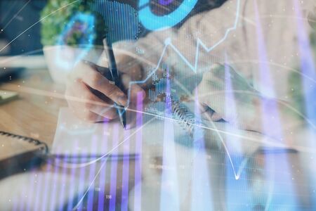 Financial forex graph displayed on hands taking notes background. Concept of research. Multi exposureの写真素材