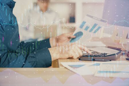 Double exposure of graph with man typing on computer in office on background. Concept of hard work....