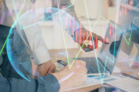 Double exposure of chart with businessman typing on computer in office on background. Concept of...