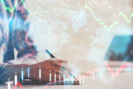 A woman hands writing information about stock market in notepad. Forex chart holograms in front....