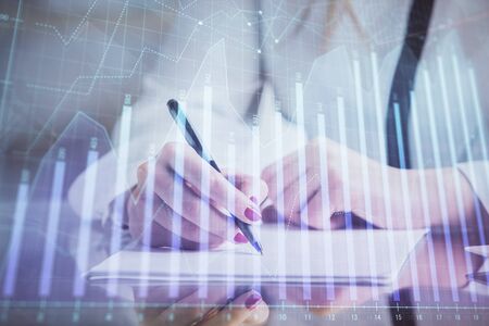 Double exposure of hands making notes with forex chart huds. Stock market concept.の写真素材