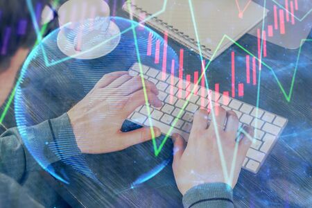 Double exposure of graph with man typing on computer in office on background. Concept of hard work.