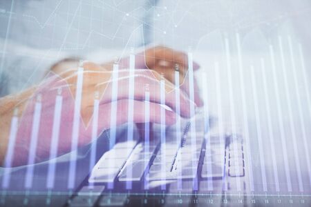 Multi exposure of graph with man typing on computer in office on background. Concept of hard work. Closeup.の写真素材
