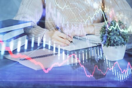 Forex graph on hand taking notes background. Concept of research. Double exposure