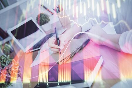 Financial graph displayed on womans hand taking notes background. Concept of research. Double exposureの写真素材