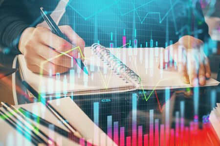 Forex chart hologram on hand taking notes background. Concept of analysis. Multi exposure