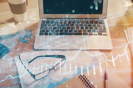 Stock market graph on background with desk and personal computer. Double exposure. Concept of financial analysis.の写真素材