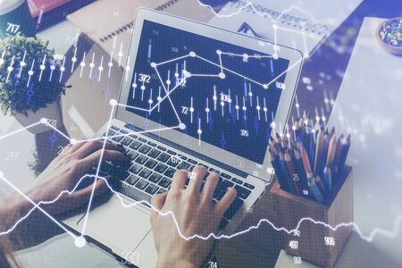 Double exposure of man's hands writing notes of stock market with forex graph background. Concept of...