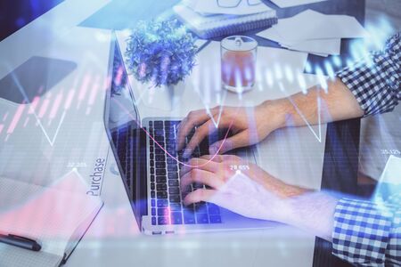 Double exposure of graph with man typing on computer in office on background. Concept of hard work.