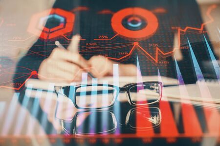 Forex chart hologram on hand taking notes background. Concept of analysis. Multi exposure