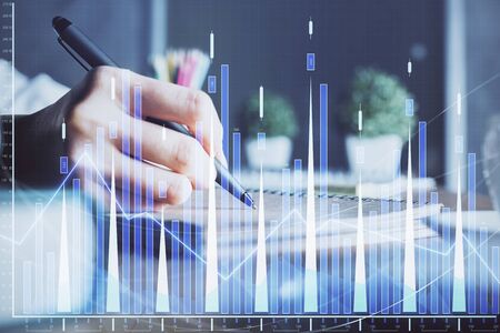Financial forex charts displayed on womans hand taking notes background. Concept of research. Double exposureの写真素材
