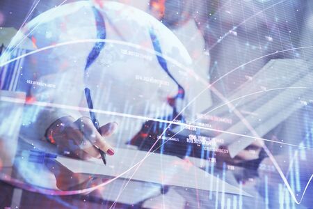 A woman hands writing information about stock market in notepad. Forex chart holograms in front. Concept of research.の写真素材