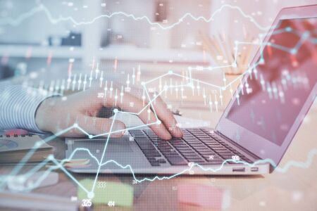 Double exposure of stock market graph with man working on laptop on background. Concept of financial...