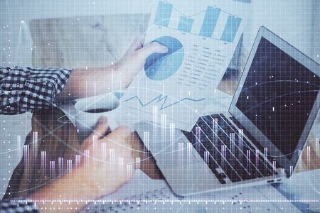 Double exposure of mans hands writing notes of stock market with forex graph background. Concept of research and trading.の写真素材