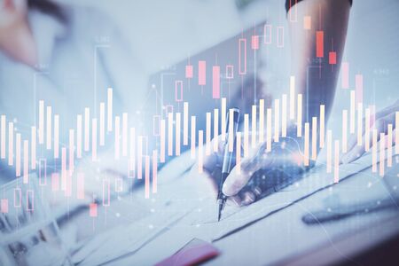 A woman hands writing information about stock market in notepad. Forex chart holograms in front. Concept of research. Double exposureの写真素材